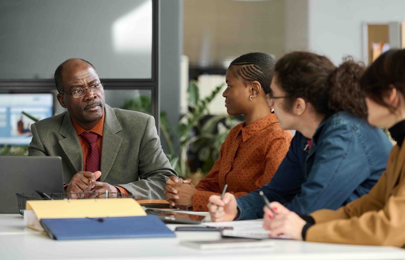 Man looking at 3 others at a meeting table