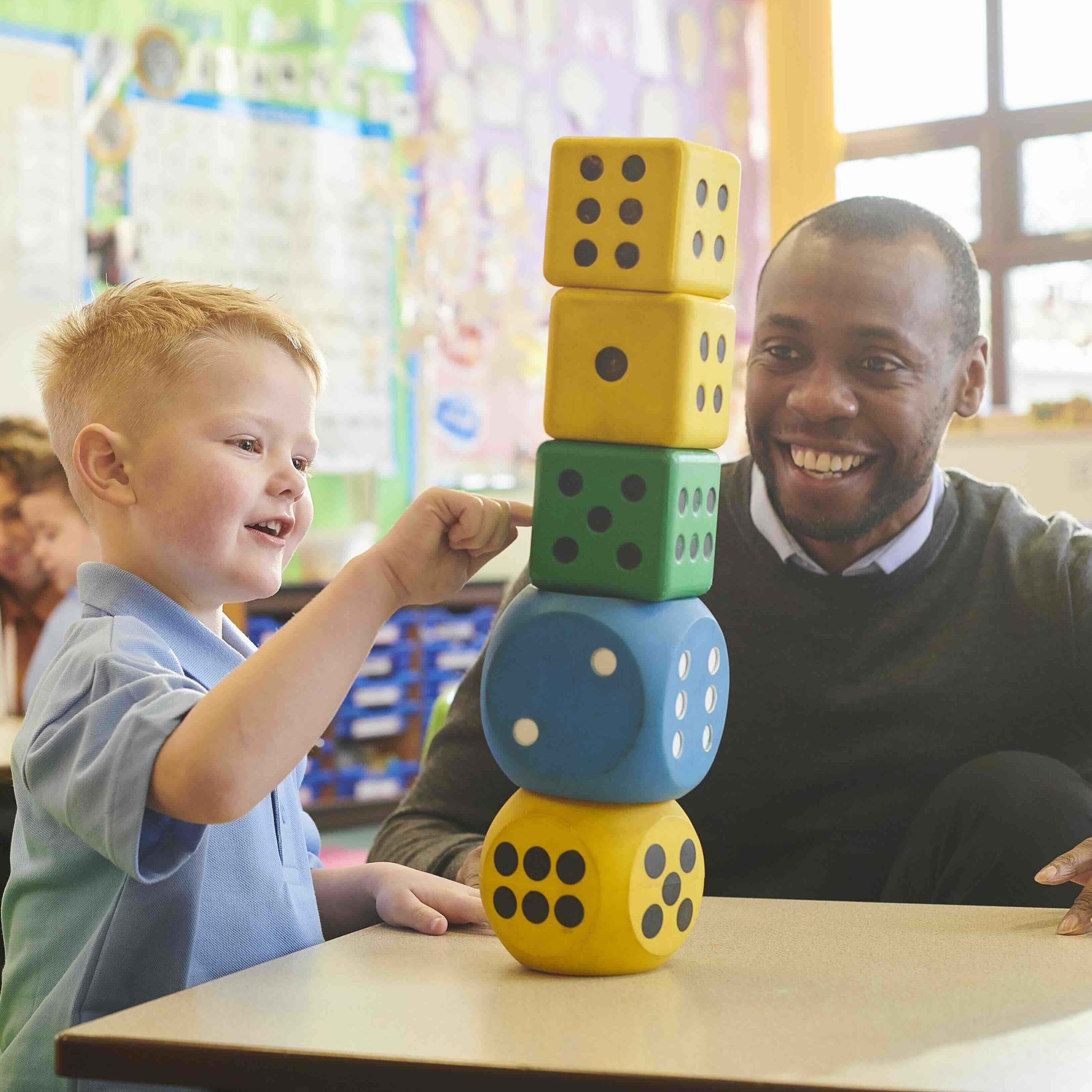 Pupil pointing at number blocks stack with man smiling